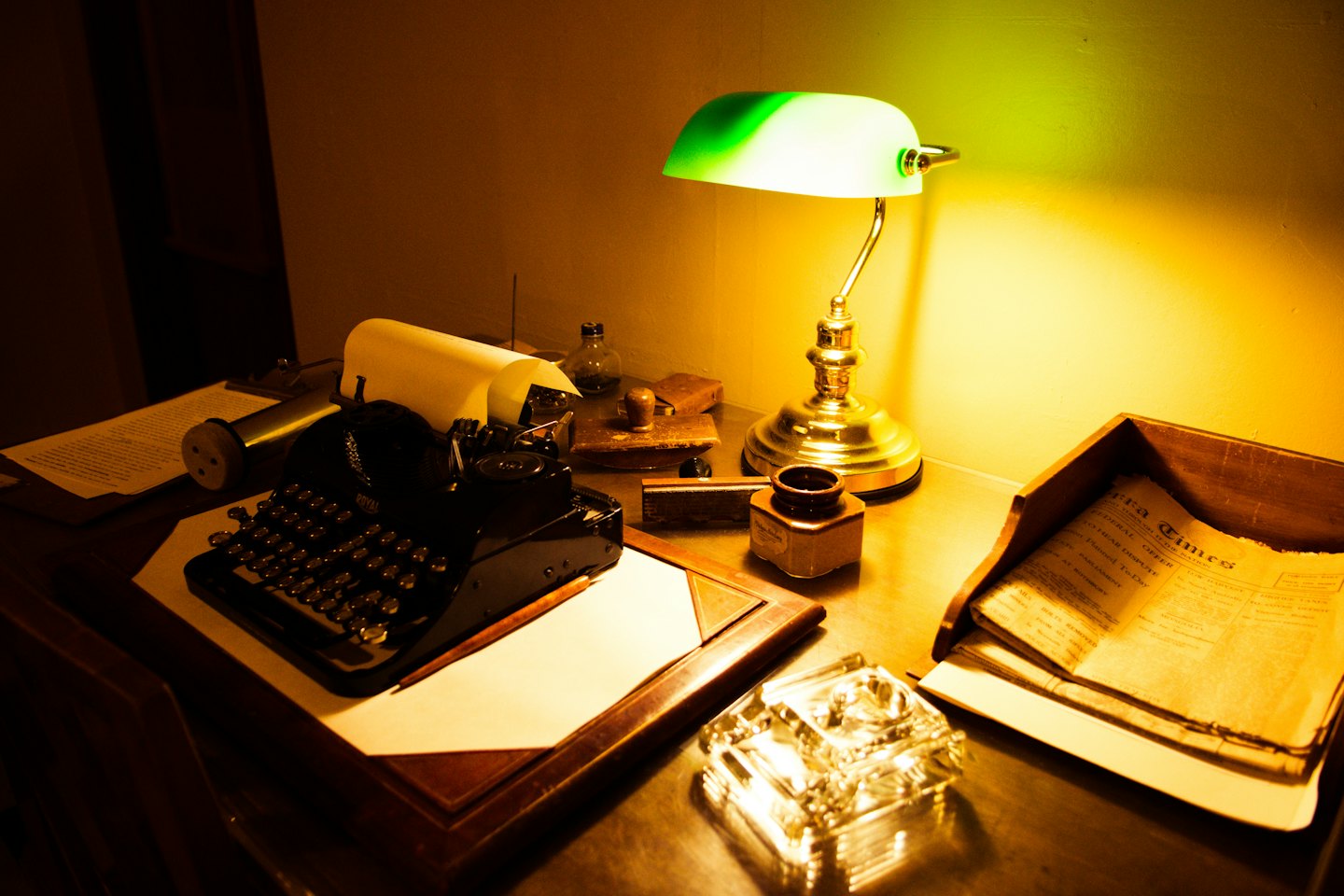 A vintage typewriter and office supplies sit on a wooden desk.