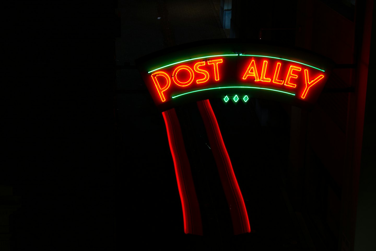 A glowing Post Alley neon sign shines in the dark.